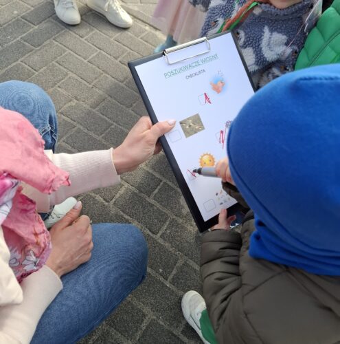 dzieci szukają na spacerze oznak wiosny , bawią się w poszukiwaczy wiosny